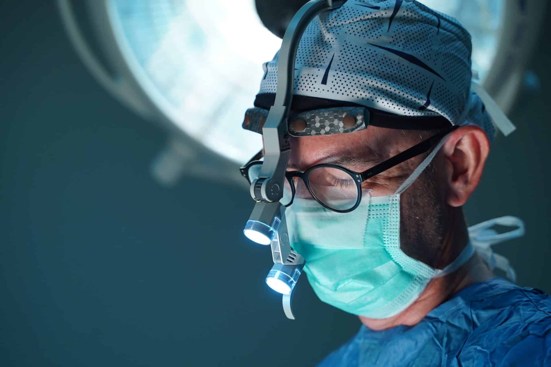 Prof. Dr. Koray Coşkunfırat ameliyathanede, cerrahi maske ve baş lambasıyla.